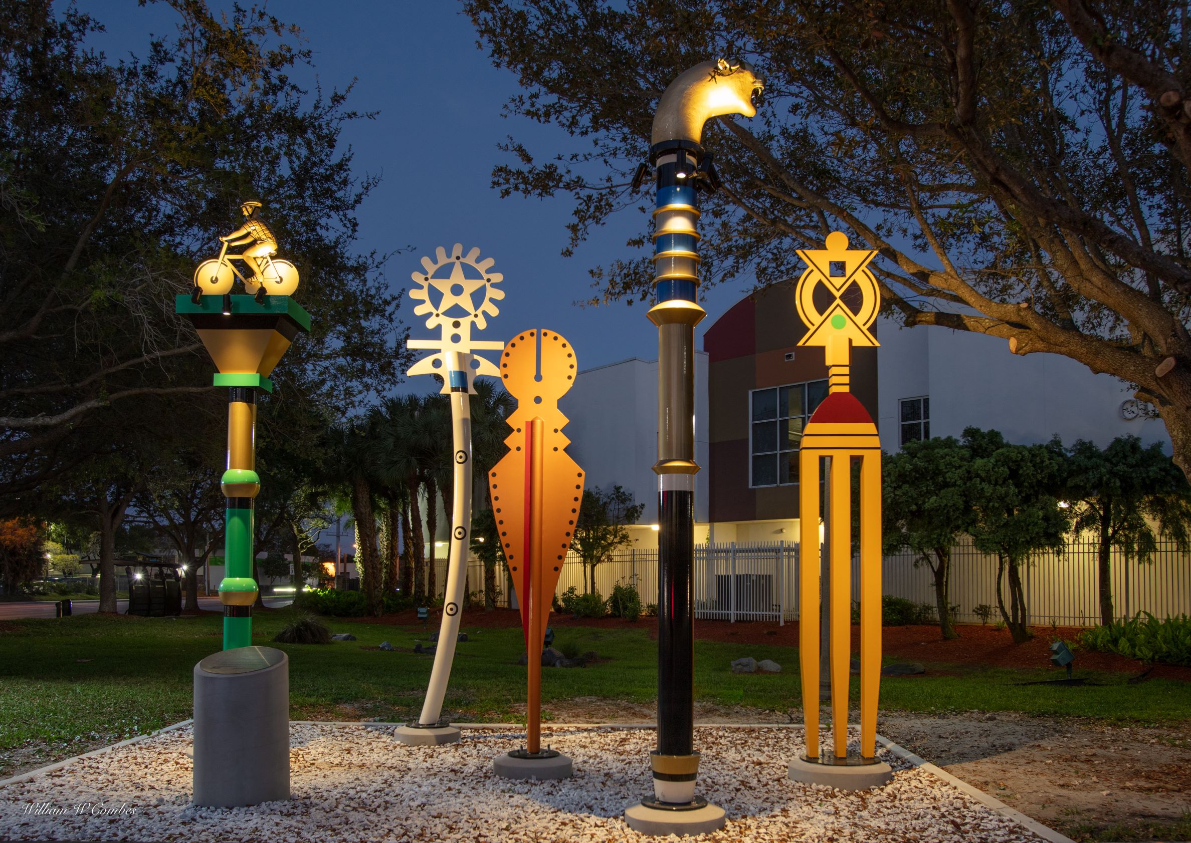 Walking Sticks with Stories to Tell is comprised of five, vividly hued freestanding sculptures that reflect the West African traditions of the linguist staff, ornamental hairpin, Adinkra symbols and kente cloth colors; by artist Claudia Fitch.